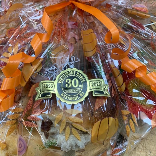 Westmont Bagel 30th Anniversary gift basket, wrapped in clear plastic with orange ribbons and fall-themed decorations.