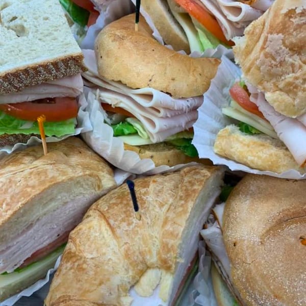 Assortment of deli sandwiches on various breads, filled with turkey, lettuce, and tomato.