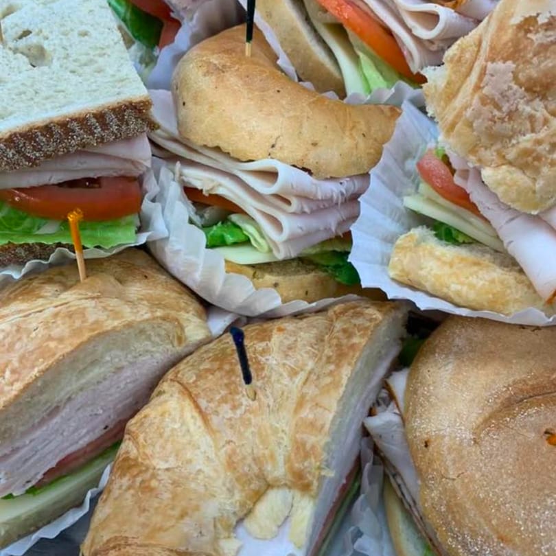 Assortment of deli sandwiches on various breads, filled with turkey, lettuce, and tomato.